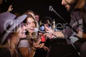 Female friends singing with male singer at nightclub