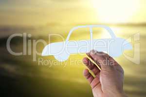 Composite image of hand holding a car in paper