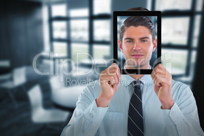 Composite image of businessman holding digital tablet in front of face