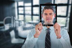 Composite image of businessman holding digital tablet in front of face