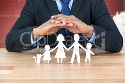 Composite image of underwriter protecting family in paper with his hands