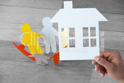 Composite image of hand holding a house in paper