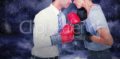 Composite image of business people wearing and boxing red gloves