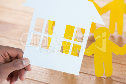 Composite image of hand holding a house in paper