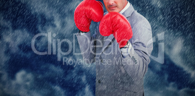 Composite image of tough businessman with boxing gloves