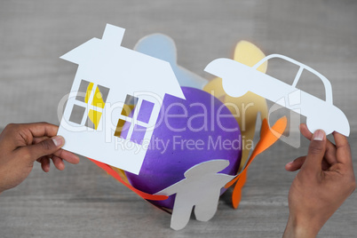 Composite image of man holding a car and a house in paper