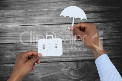 Composite image of hands holding a schoolbag and an umbrella in paper