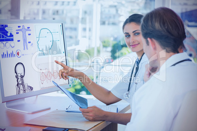 Composite image of doctor showing the screen of a computer to a colleague