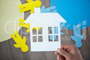 Composite image of hand holding a house in paper