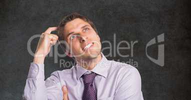 Confused businessman scratching head against blackboard