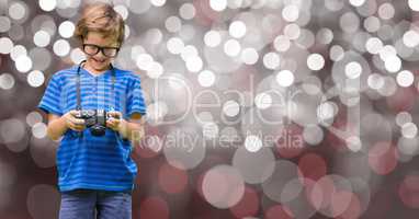 Boy watching pictures on camera over bokeh