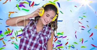 Happy woman listening to music against colorful feathers