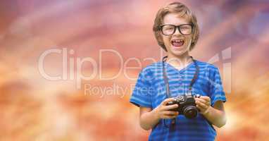 Portrait of cheerful boy holding camera over bokeh