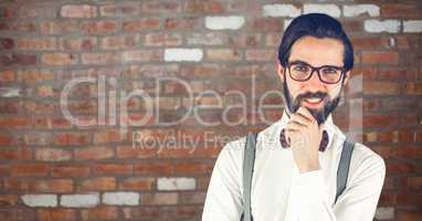Male hipster smiling against brick wall