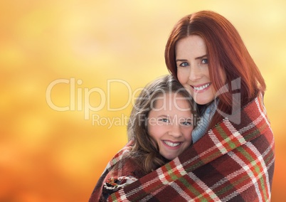 Mother hugging daughter against orange background