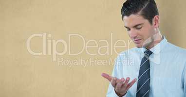 Businessman looking at hand against yellow background