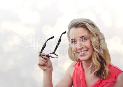 Portrait of smiling woman holding eyeglasses over bokeh