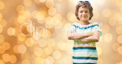 Portrait of confident boy standing arms crossed over bokeh