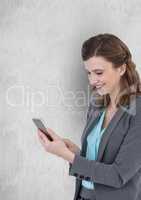 Smiling businesswoman texting on smart phone against wall