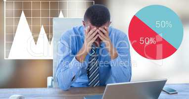 Stressed businessman with head in hands by graphics