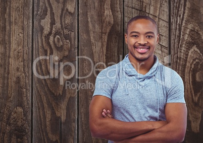 Portrait of happy male hipster standing arms crossed against wooden wall