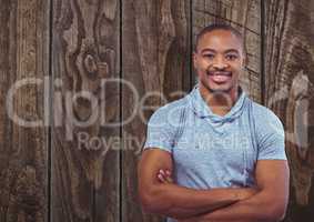 Portrait of happy male hipster standing arms crossed against wooden wall