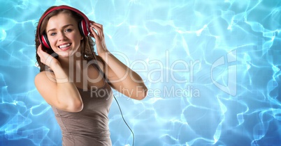 Happy woman listening music on headphones against reflection of sunlight in water