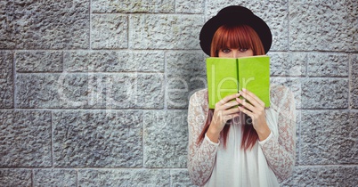 Redhead woman holding book against wall