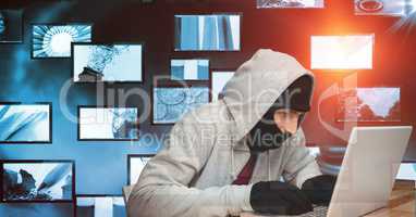 Hacker using laptop against screens
