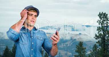 Confused man using smart phone on mountain