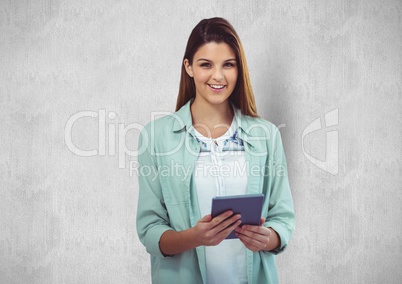 Young businesswoman holding tablet PC against wall