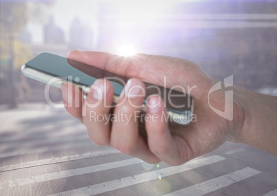 Hand with phone against blurry street with flares