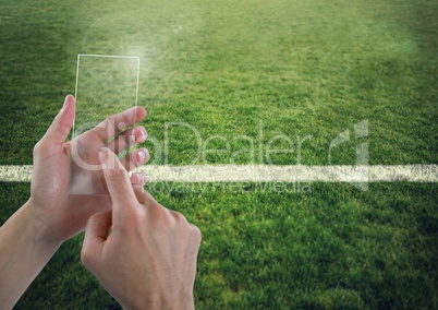 Hand touching glass screen on sports pitch