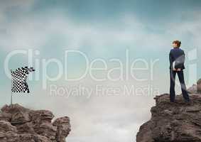 Businessman looking at checked flag on rock against sky