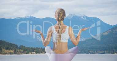 Rear view of woman meditating against mountains