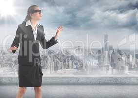 Business woman blindfolded with flare against skyline and grey clouds