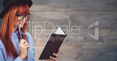 Redhead businesswoman reading book over wooden wall