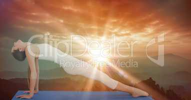 Side view of flexible woman performing yoga during sunset