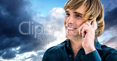 Handsome man using mobile phone against sky