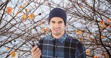 Hipster holding smoking pipe against autumn tree