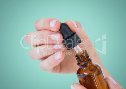 Hand with dropper and bottle against aqua background