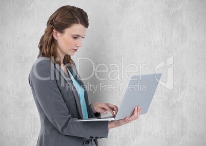 Businesswoman using laptop against wall