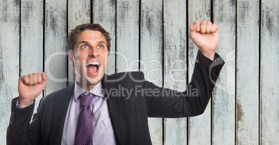 Successful businessman screaming while clenching fists against wooden wall