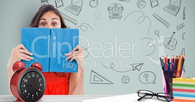 Female student holding book in front of face against graphics