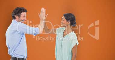 Happy business people giving high-five against orange background