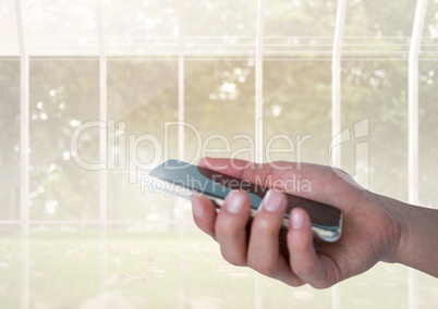 Hand with mobile phone and windows with trees