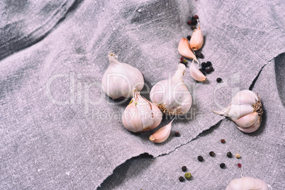 white heads raw garlic on a gray cloth, close up