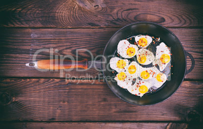 Fried quail eggs in a cast-iron black frying pan