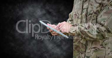 Soldier mid section with tablet against black grunge background
