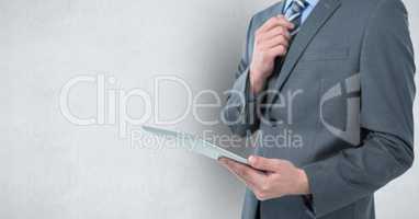 Midsection of businessman holding digital tablet over gray background